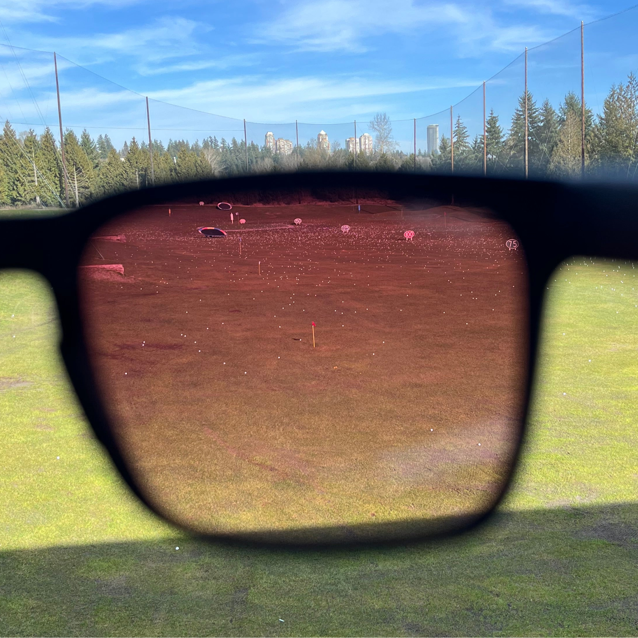 Sunglasses with a view of a golf driving range and golf balls