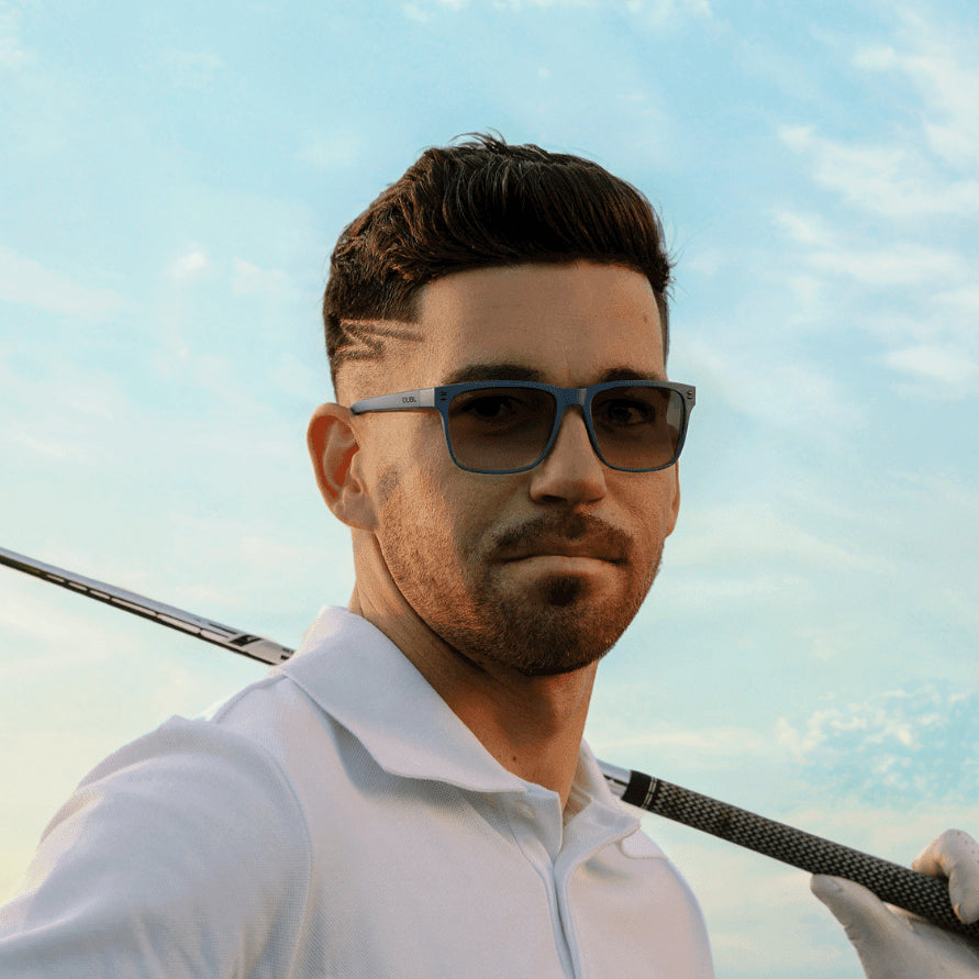 Matte Abyss | Man wearing golf sunglasses holding a golf club on a golf course with a clear sky