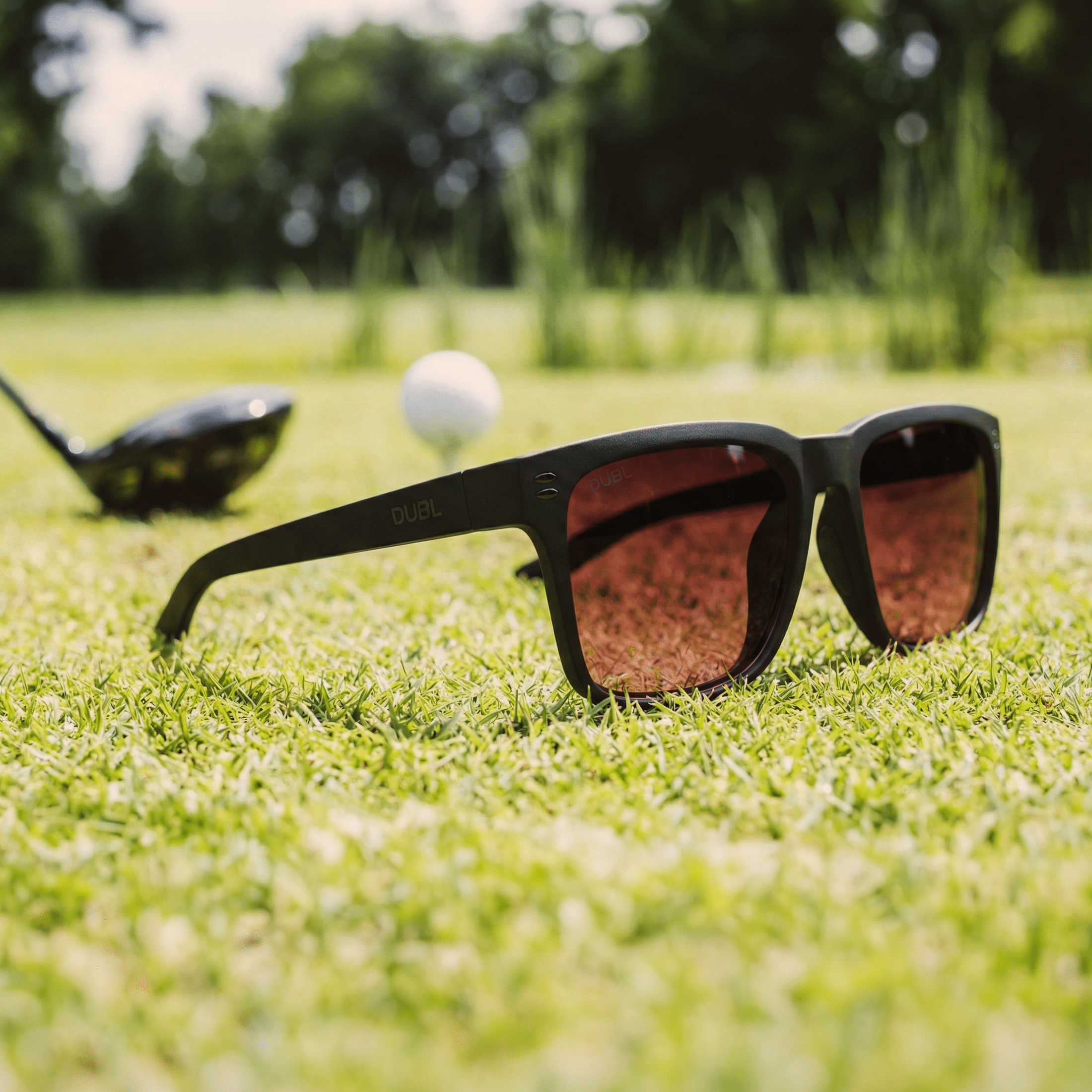 DUBL Hyperion Black Golf Sunglasses on a golf course with a golf club and ball in the background