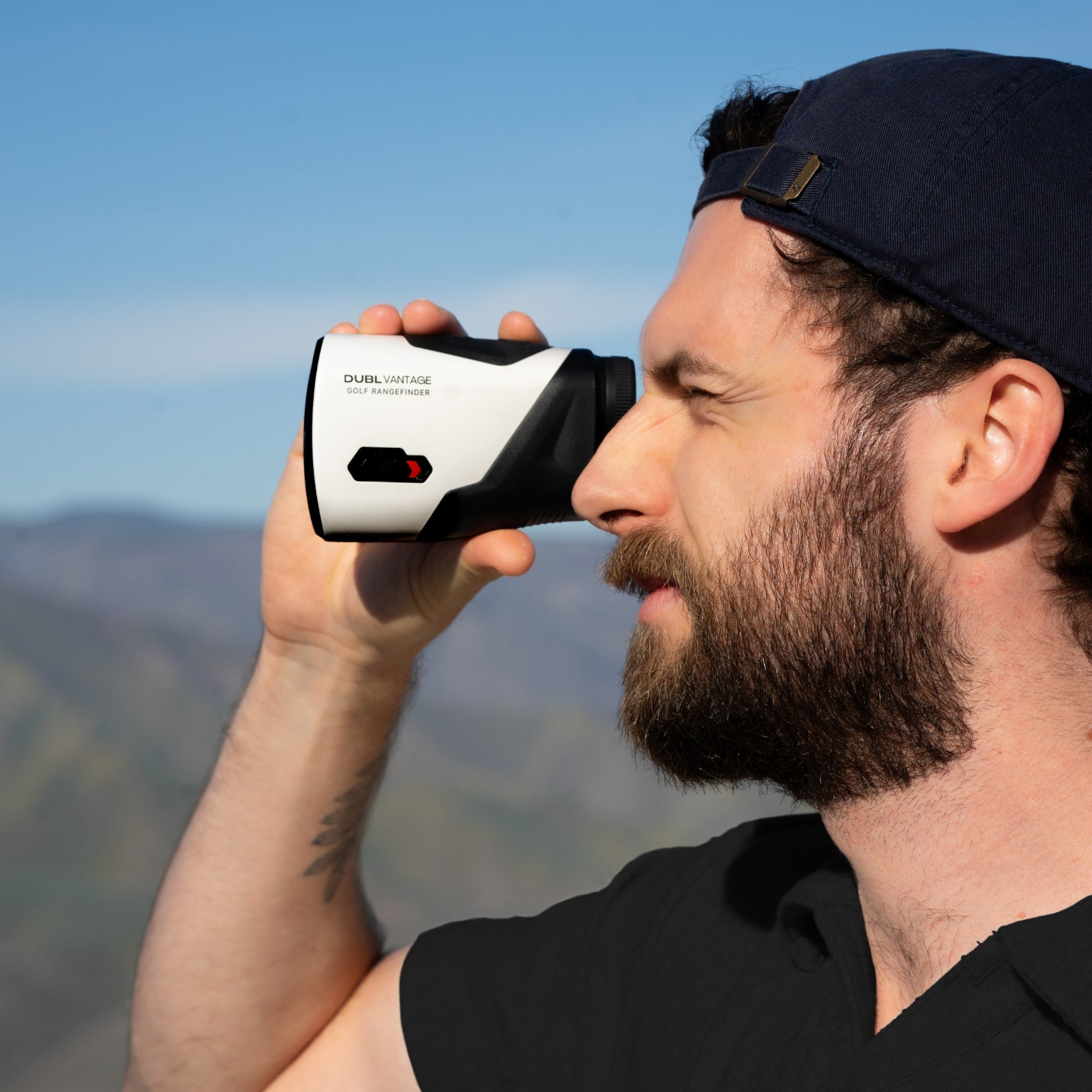 Man using a rangefinder with mountains in the background